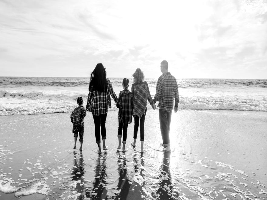 Eine Familie geht Hand in Hand am Strand ins Licht